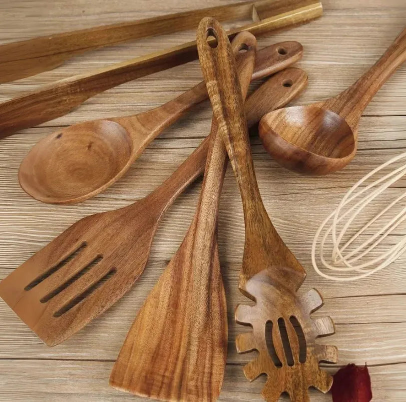 Seven wooden cooking spoons and spatulas with non-slip handles arranged as a set for non-stick pans.