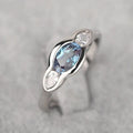 Geometric ellipse copper ring with inlaid zircon stones in white gold finish on a grey background