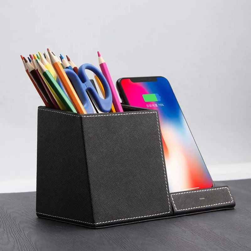 Black leather pen holder with integrated wireless phone charging pad on a desk.