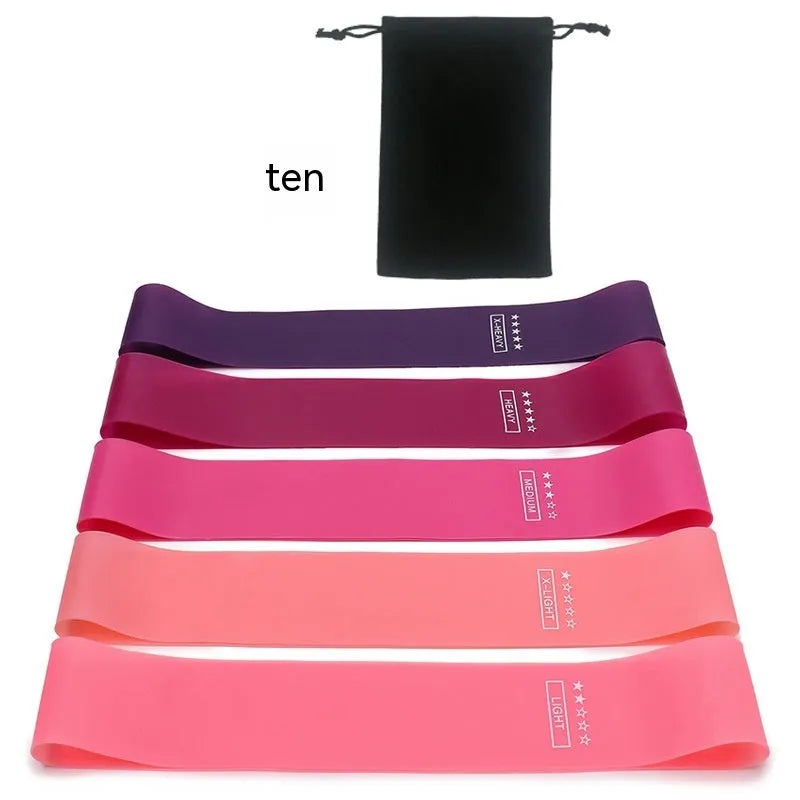 Five colour-coded yoga tension straps for resistance training laid flat showing green, blue, yellow, red, and black options
