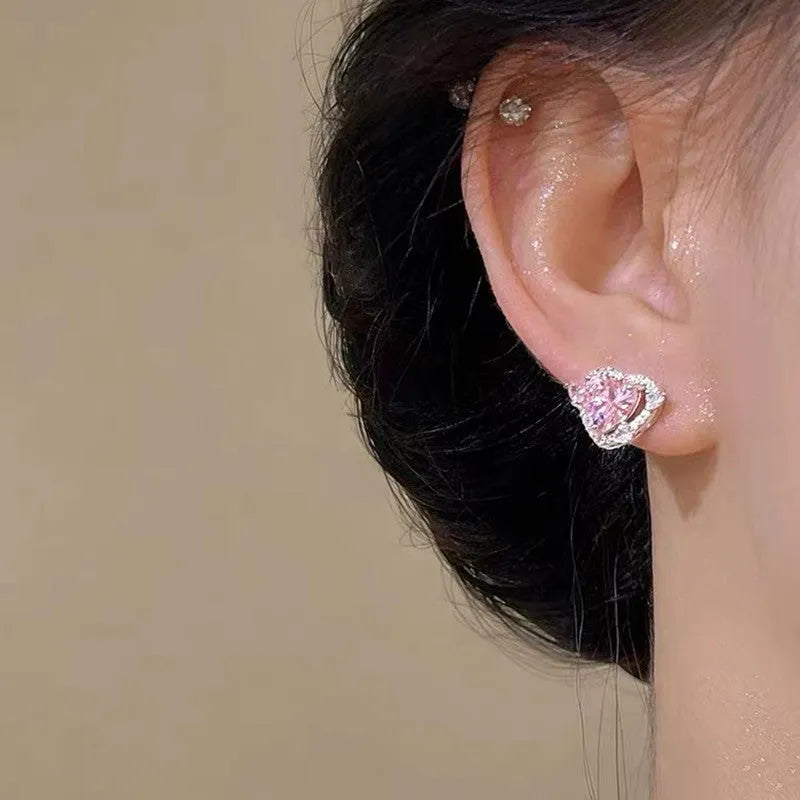 A pair of women's heart-shaped stud earrings with a white K electroplated finish on a copper base.