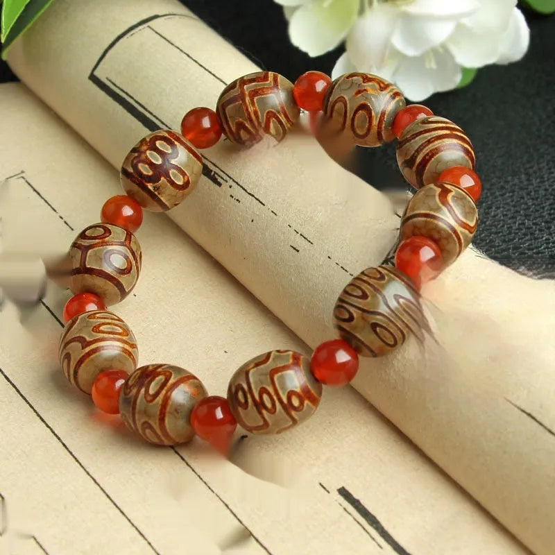 Distressed agate Tibetan bead bracelet with three-eye motifs and polished finish.