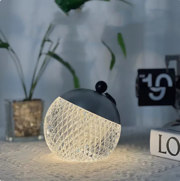 Small round touch-control dimmable LED night lamp in a metallic finish on a wooden table.