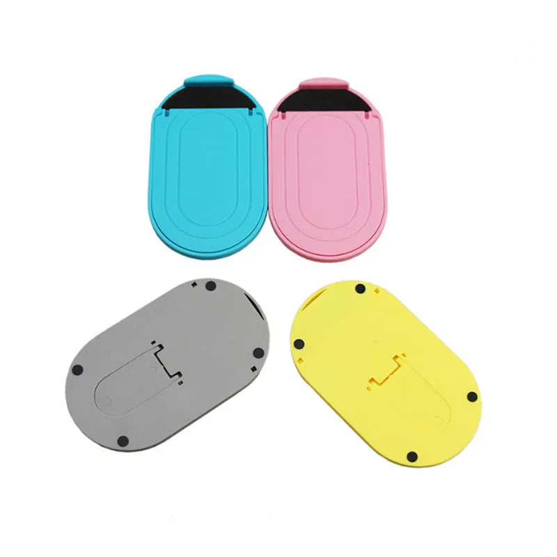A plastic lazy bracket mobile phone stand holding a smartphone, shown in multiple colour options.