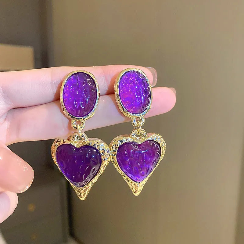 Four pairs of oval love heart stud earrings with silver needle pleated detailing in purple, red, green, and yellow-white colours
