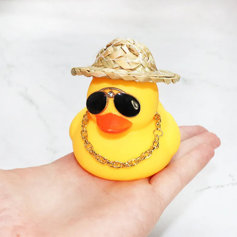 Yellow duck car ornament wearing straw hat with removable sunglasses necklace on dashboard