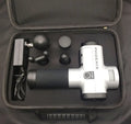 Black fascia massage gun with four removable heads on a grey background