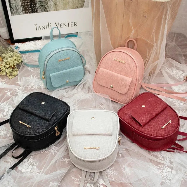 Small black women's PU shoulder backpack worn as backpack, showing zipper closure and compact size