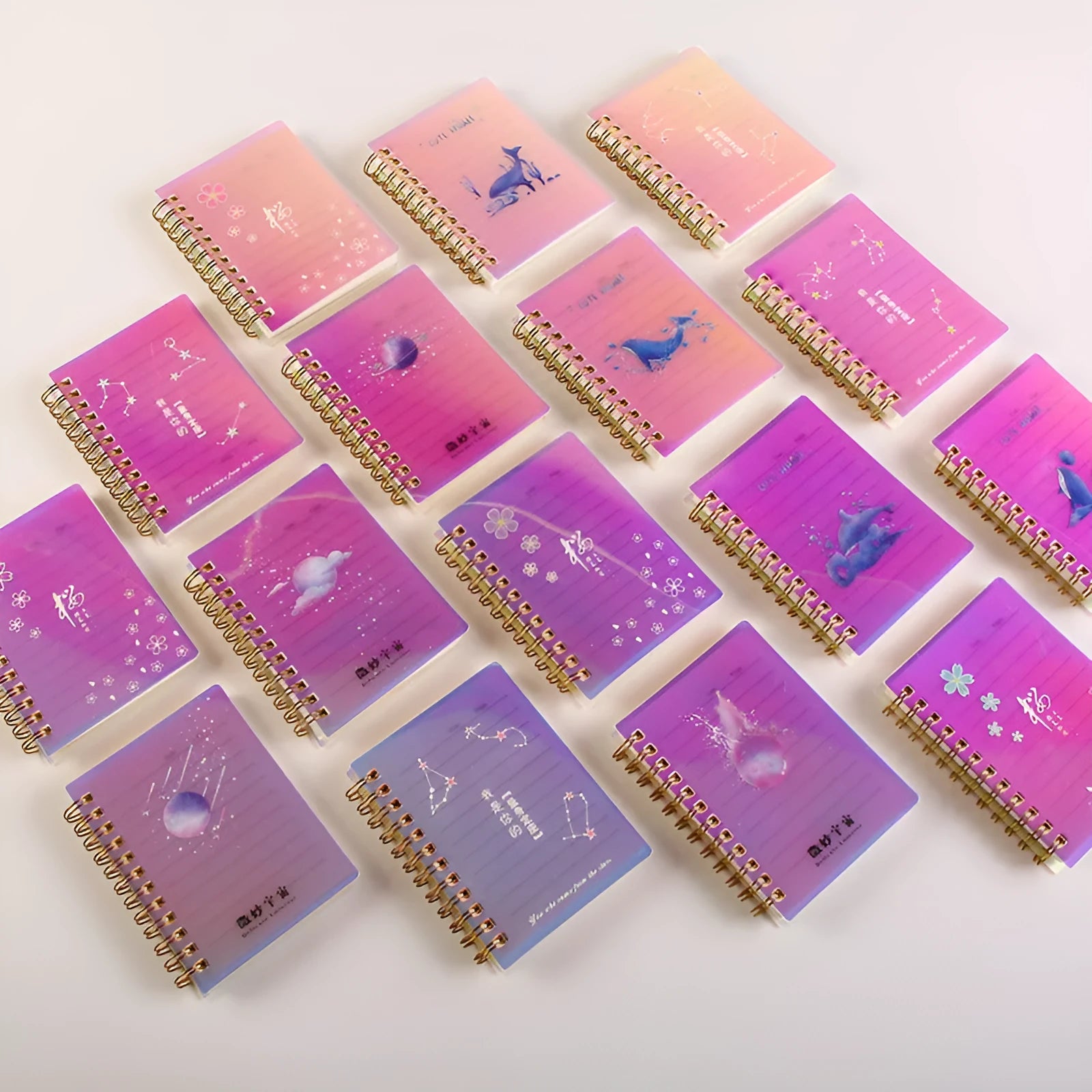 Four A7 spiral-bound pocket notebooks showing different PP cover designs: Constellation, Sakura, Universe, and Ocean.