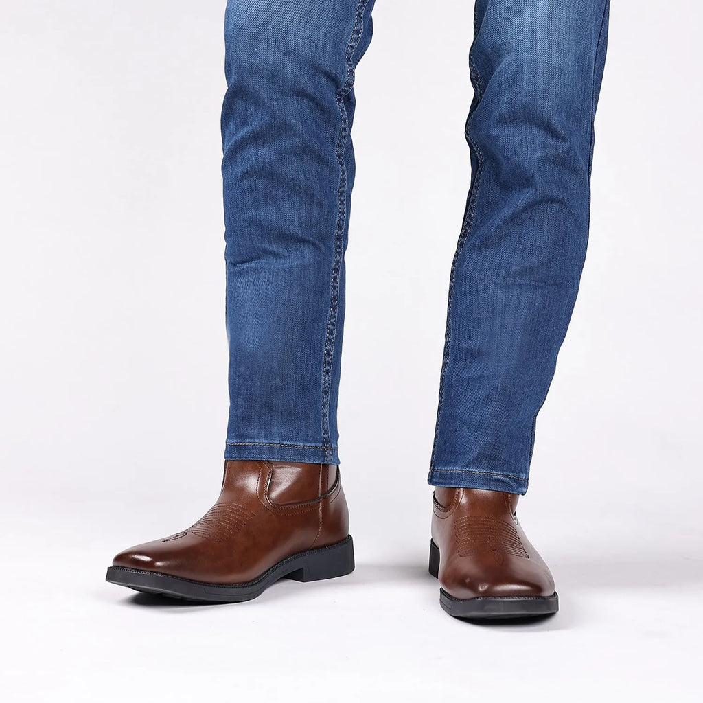 Men's brown retro cowboy boot with square toe and horseshoe heel on a wooden floor.
