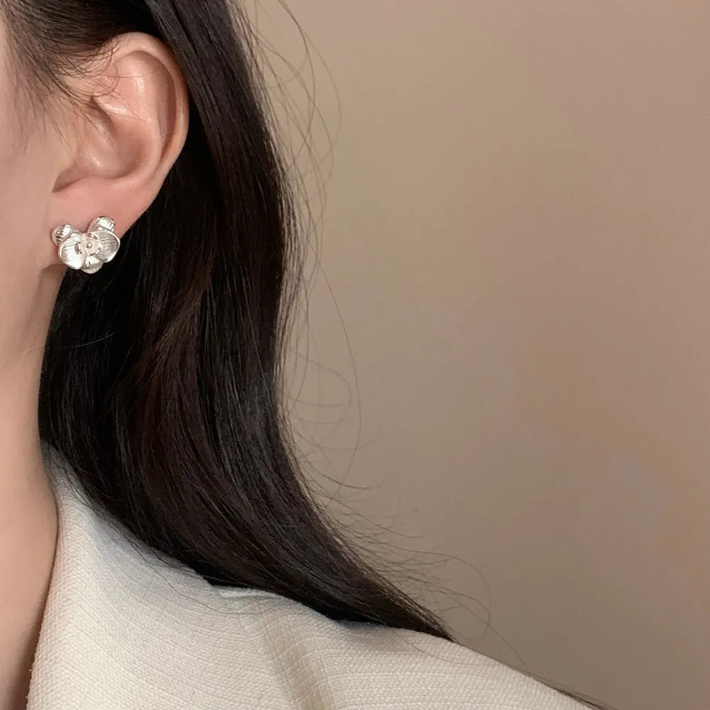 A pair of gold and silver retro-style flower earrings with petal details on a white background.