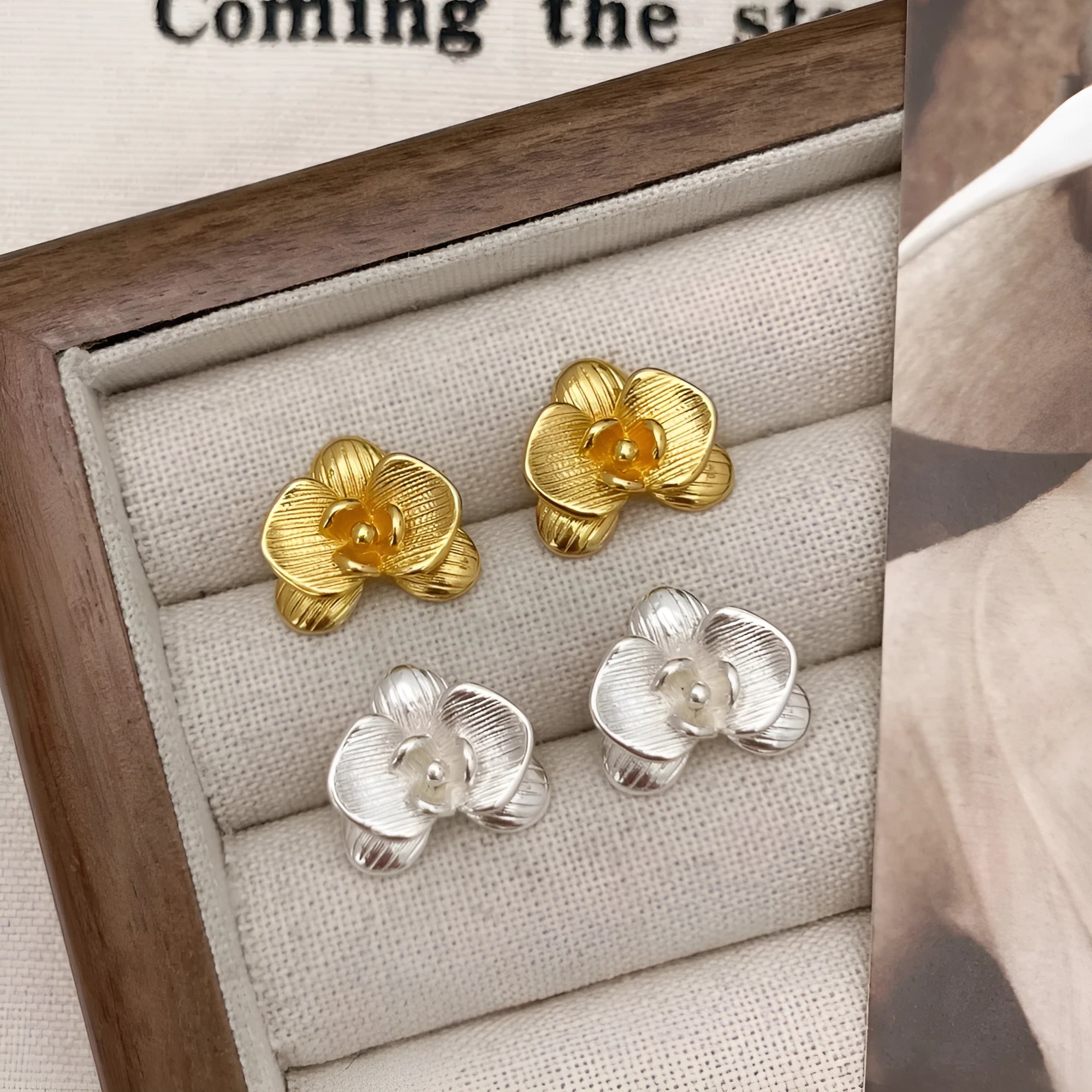 A pair of gold and silver retro-style flower earrings with petal details on a white background.