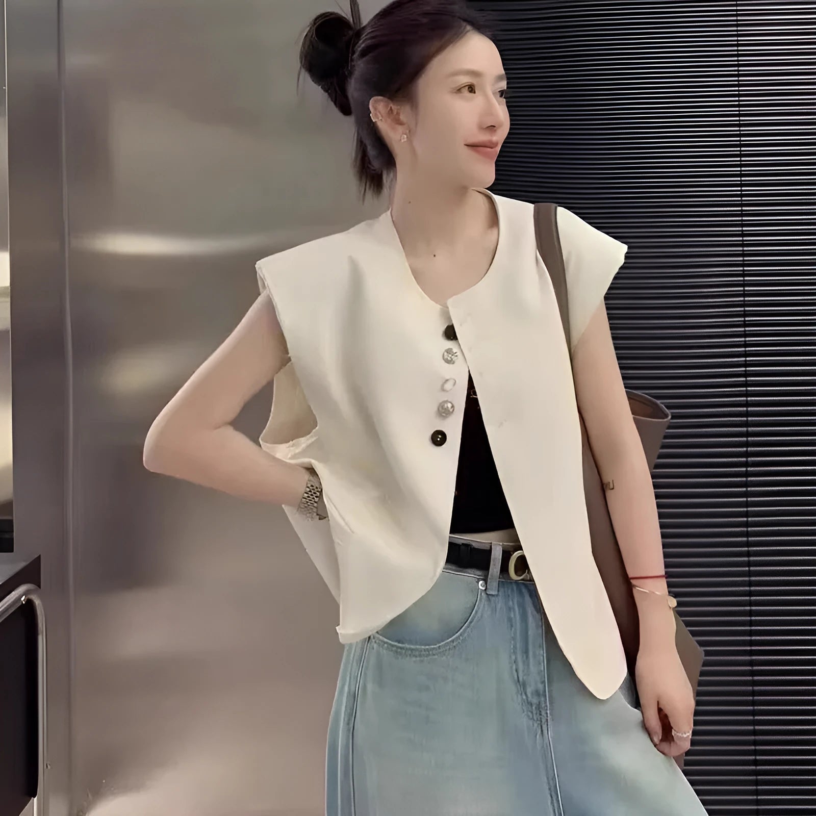 Women's loose fit sleeveless vest in black with a pocket, shown on a hanger.