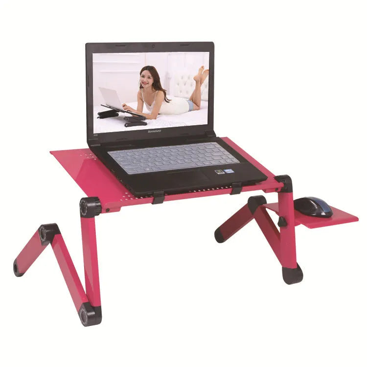 Black folding metal computer desk with mouse board, shown in use on a bed.