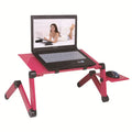 Black folding metal computer desk with mouse board, shown in use on a bed.