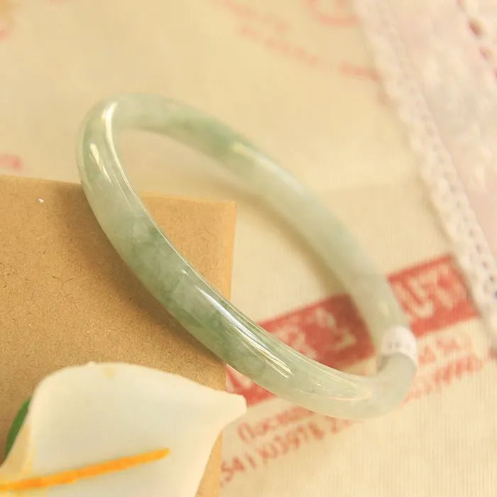 Green geometric jade waxy bracelet with 10mm diameter on a wrist.