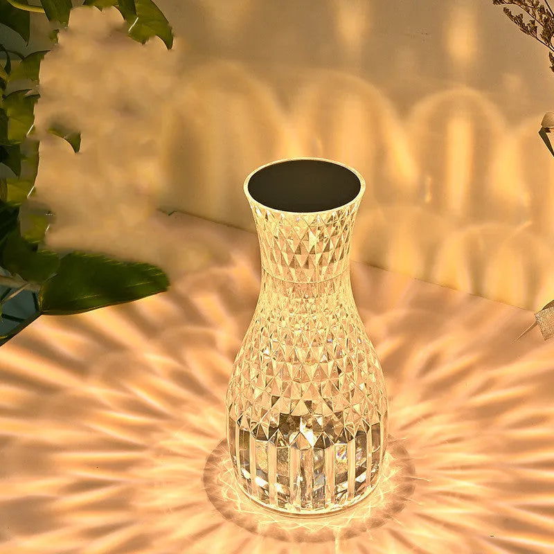 Vase-shaped transparent crystal table lamp with LED colour-changing lights on wooden surface