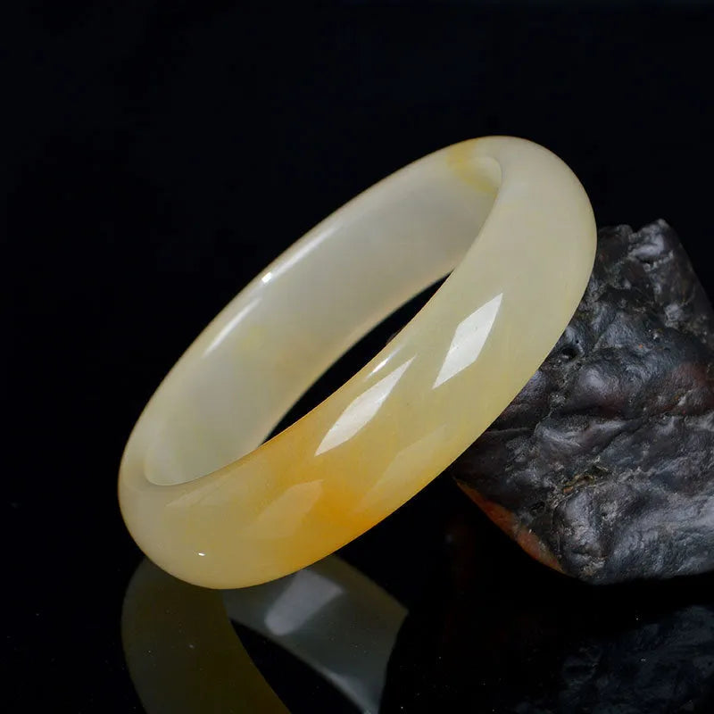 Natural light jade bracelet with a polished finish on a wrist, showing its Chinese style.