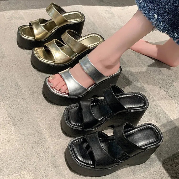 Women's black wedge platform slippers with a square toe on a plain background.