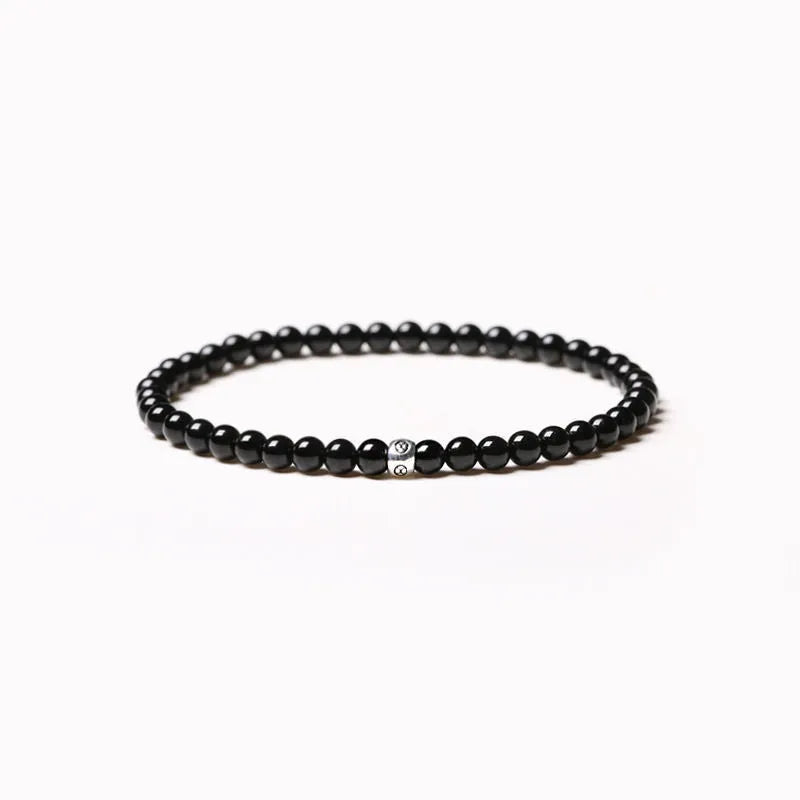 Geometric stone bracelet with obsidian, blue san, and black agate 4mm beads on a wrist.