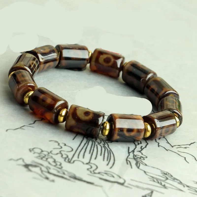 Distressed agate Tibetan bead bracelet with three-eye motifs and polished finish.