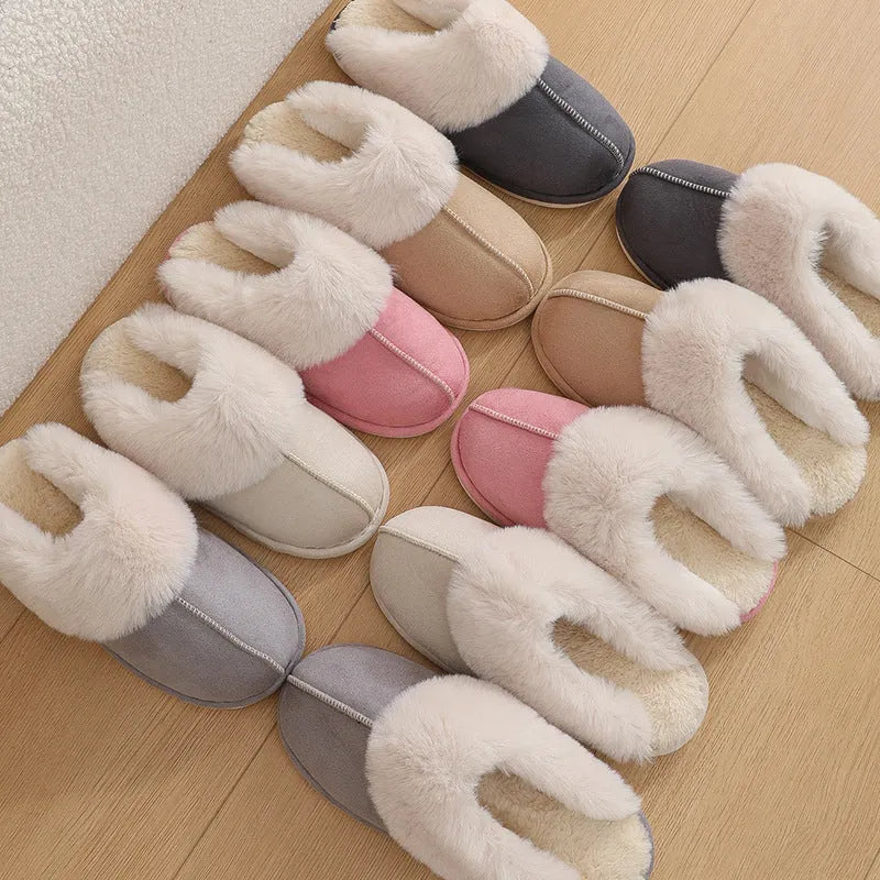 A pair of plush indoor slippers with a round toe, flat heel, and stitching detail, shown in one of five available colours.