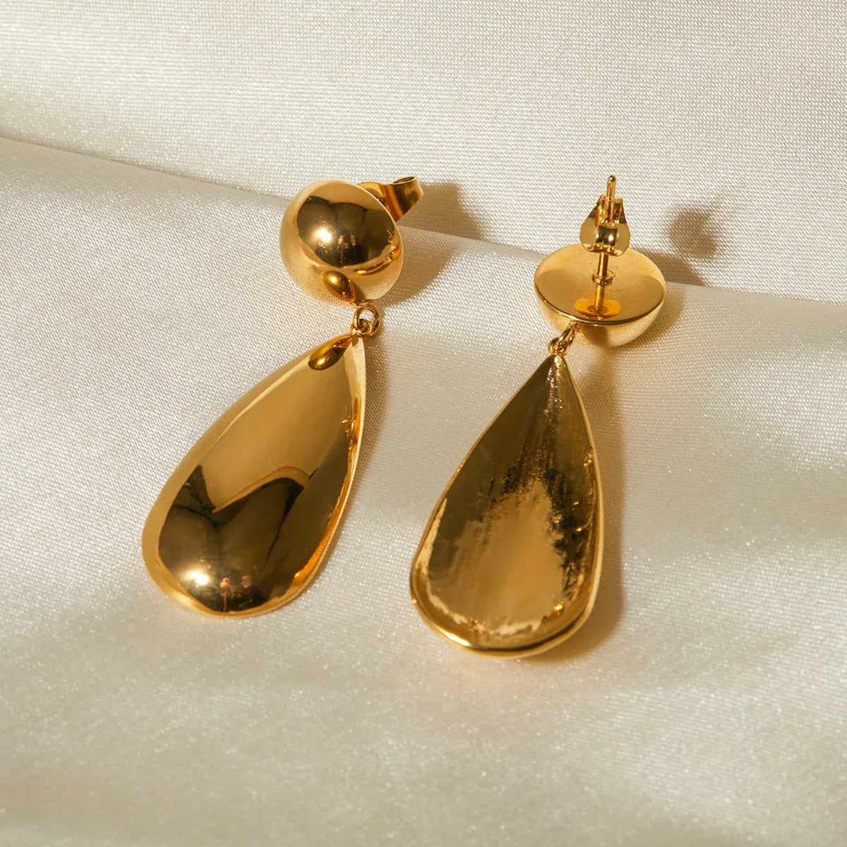 Gold stainless steel earrings with geometric hemisphere shape and water drop pendant design