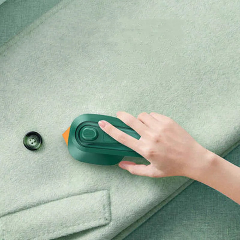 Dark green portable hanging steam iron machine with ceramic panel, shown for scale next to a mobile phone.
