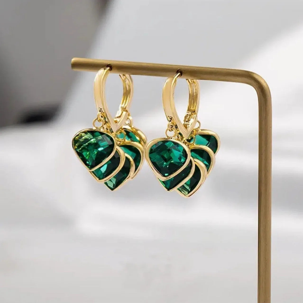 Pair of green heart-shaped glass pendant ear clip earrings with alloy inlay detail.