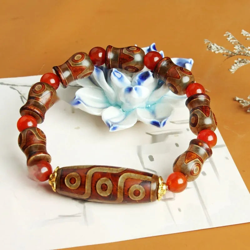 Distressed agate Tibetan bead bracelet with three-eye motifs and polished finish.