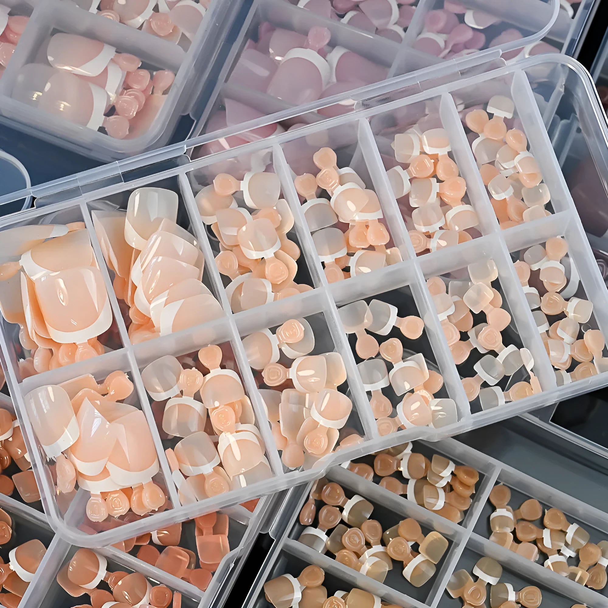 Box of 120 short square false toenails with French white tips, showing nine nude colour options from light to dark.