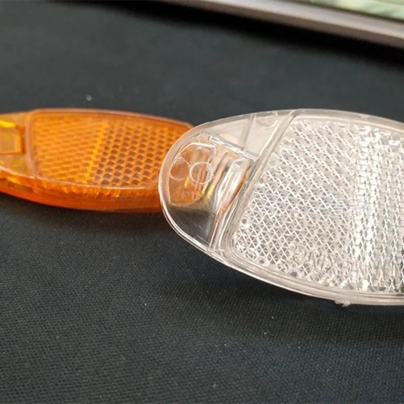 White and yellow plastic bicycle reflector spoke decorations showing 7.2cm length and 3.5cm width dimensions