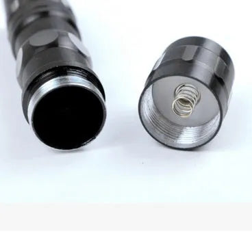 Black aluminium mini LED flashlight showing compact 9.5cm size with AA battery for scale