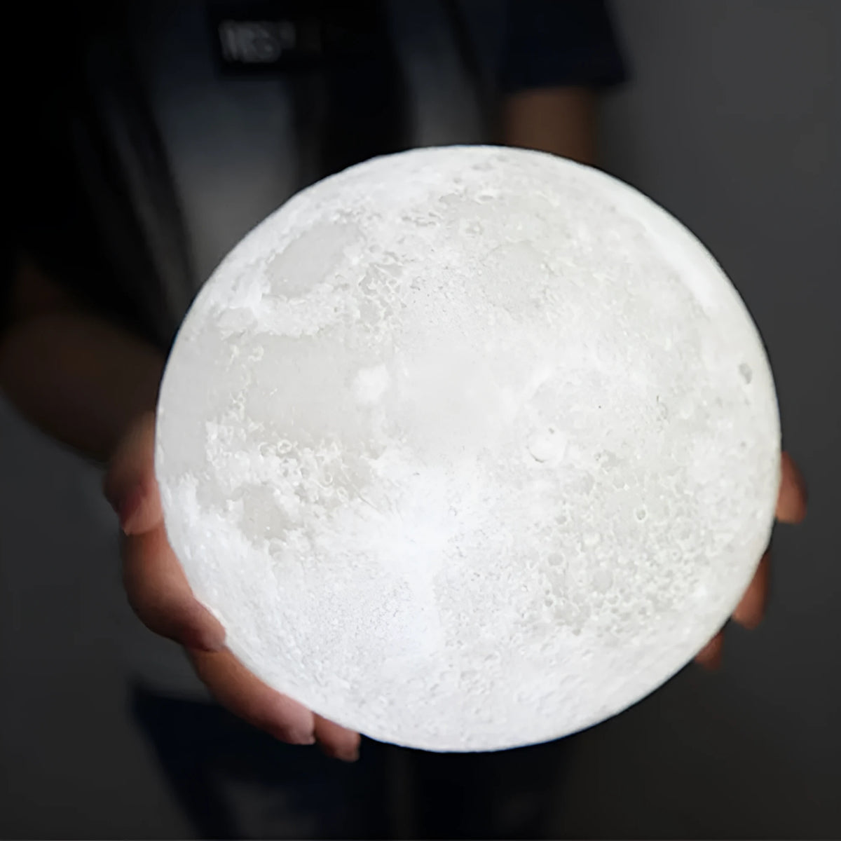 3D printed white moon lamp with detailed craters on a wooden stand, showing touch ring at base.
