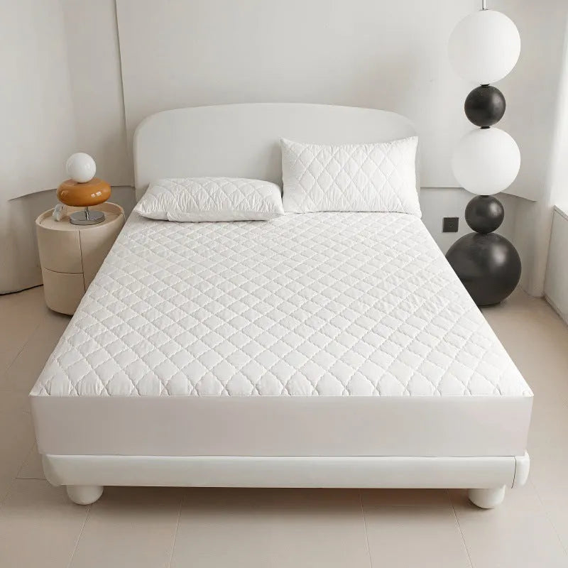 Diamond lattice quilted waterproof mattress protector fitted sheet in a solid colour on a bed.