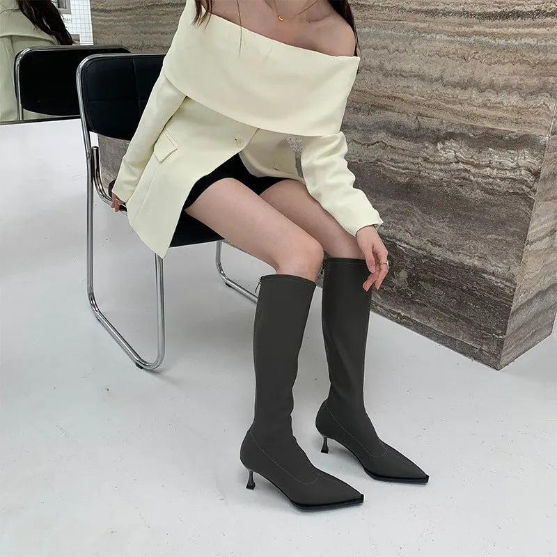 Black pointed toe women's boots with a back zipper and a stiletto heel.