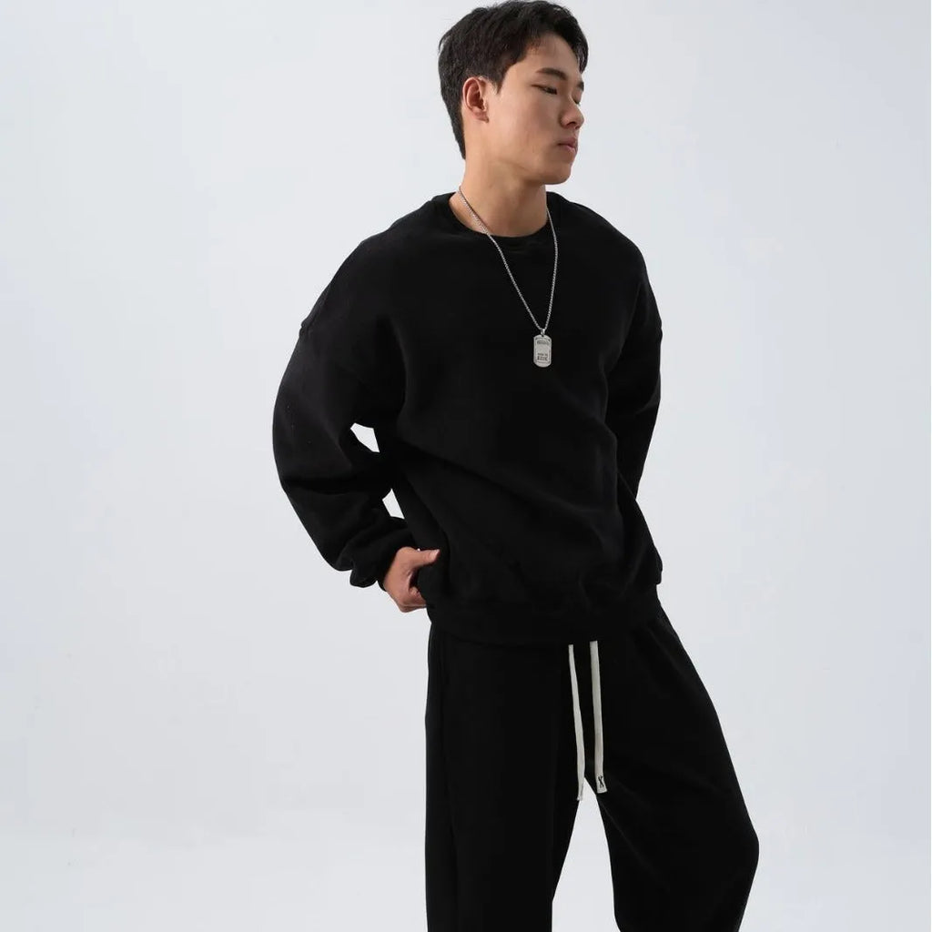 Men's loose-fit polar fleece sports suit in black, showing the long sleeve crew neck coat and matching padded trousers.