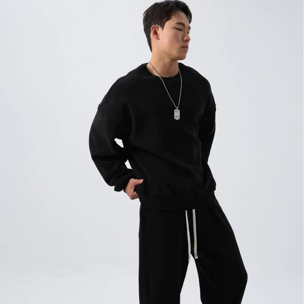 Men's loose-fit polar fleece sports suit in black, showing the long sleeve crew neck coat and matching padded trousers.