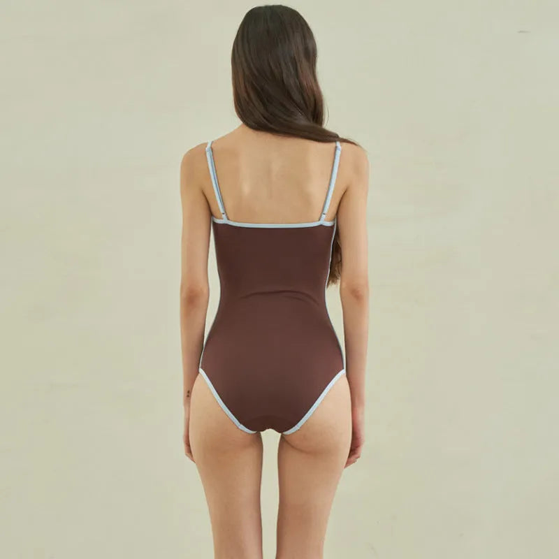 Brown women's one-piece swimsuit with triangle neckline on a hanger.