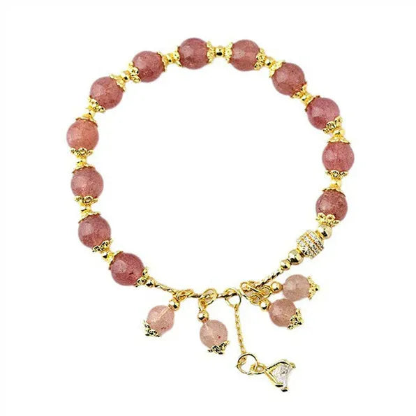 Close-up of a pink heart-shaped strawberry quartz crystal bracelet with pearl details on a wrist.