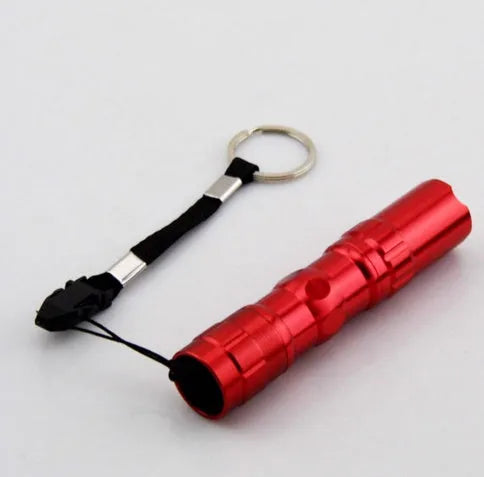 Black aluminium mini LED flashlight showing compact 9.5cm size with AA battery for scale