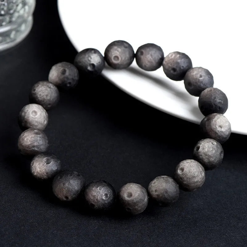 Natural obsidian crater ball bracelet showing distinctive grinding texture on beads