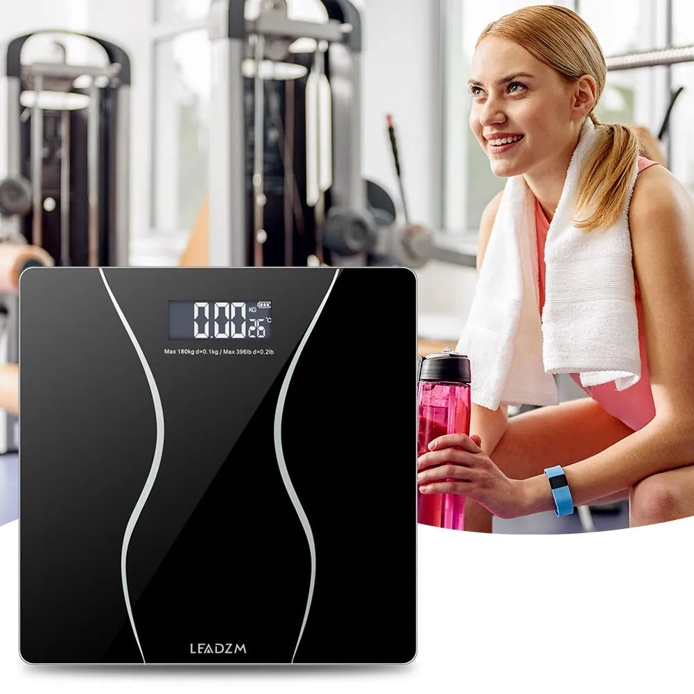 Black electronic bathroom scale with LCD display on a bathroom floor.