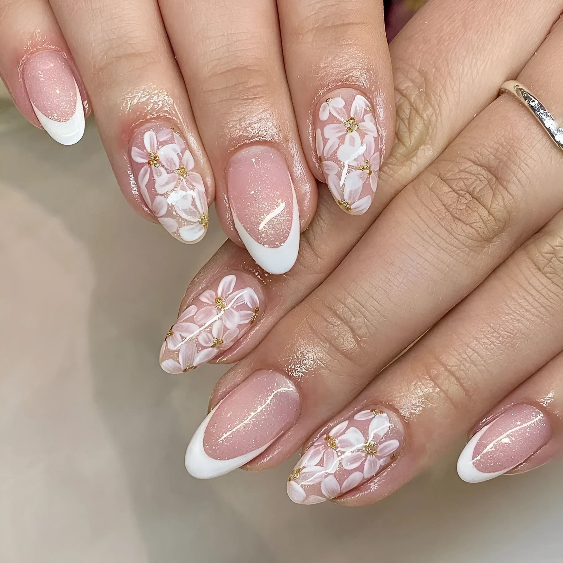 Short almond artificial nail tips with French manicure and glitter flower design in C625 colour