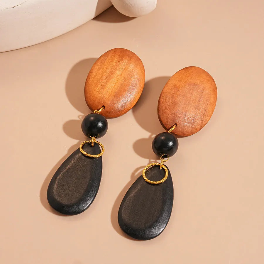 Brown and black wooden elliptical earrings with silver needle details on retro background