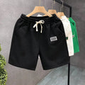Men's solid colour polyester sports shorts with elastic waist in white, black and green options