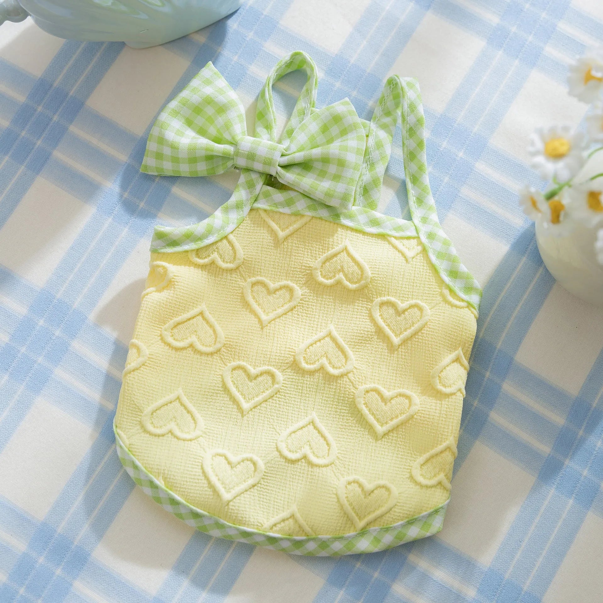 Small dog wearing a blue elastic vest with a heart texture pattern and bow suspenders.