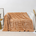 A thick, solid-colour flannel blanket draped over a modern grey sofa.