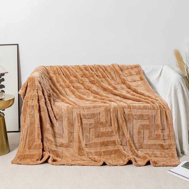 A thick, solid-colour flannel blanket draped over a modern grey sofa.