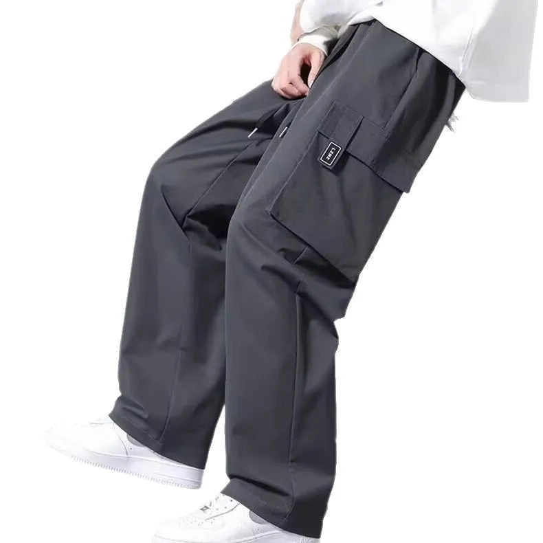 Boy wearing army green straight leg cargo pants with large pockets and a drawstring waist.